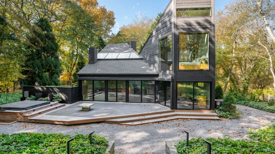 Una casa moderna con un amplio patio y árboles alrededor.