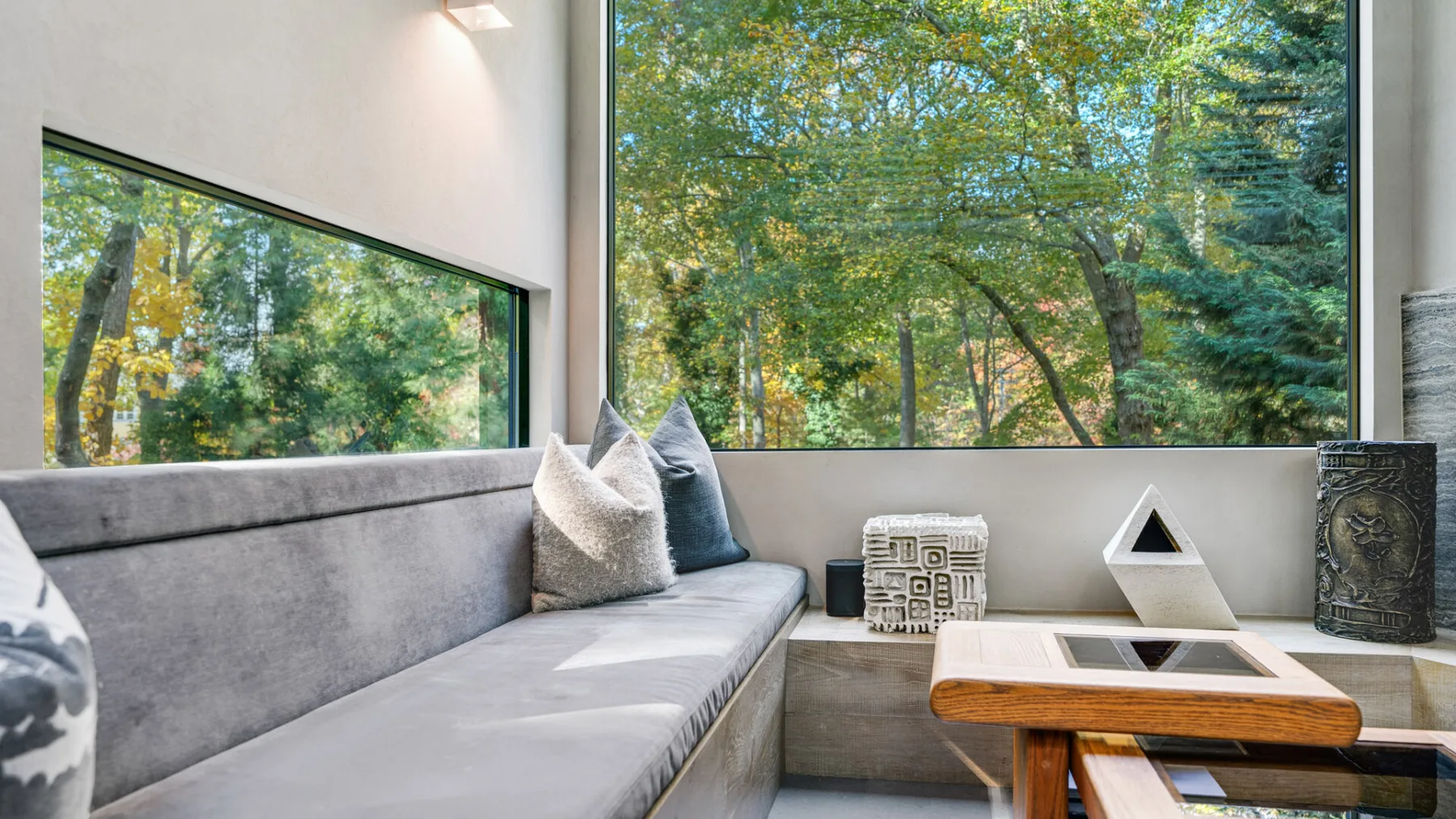 Una sala luminosa con asientos integrados junto a grandes ventanas con vistas a árboles frondosos.
