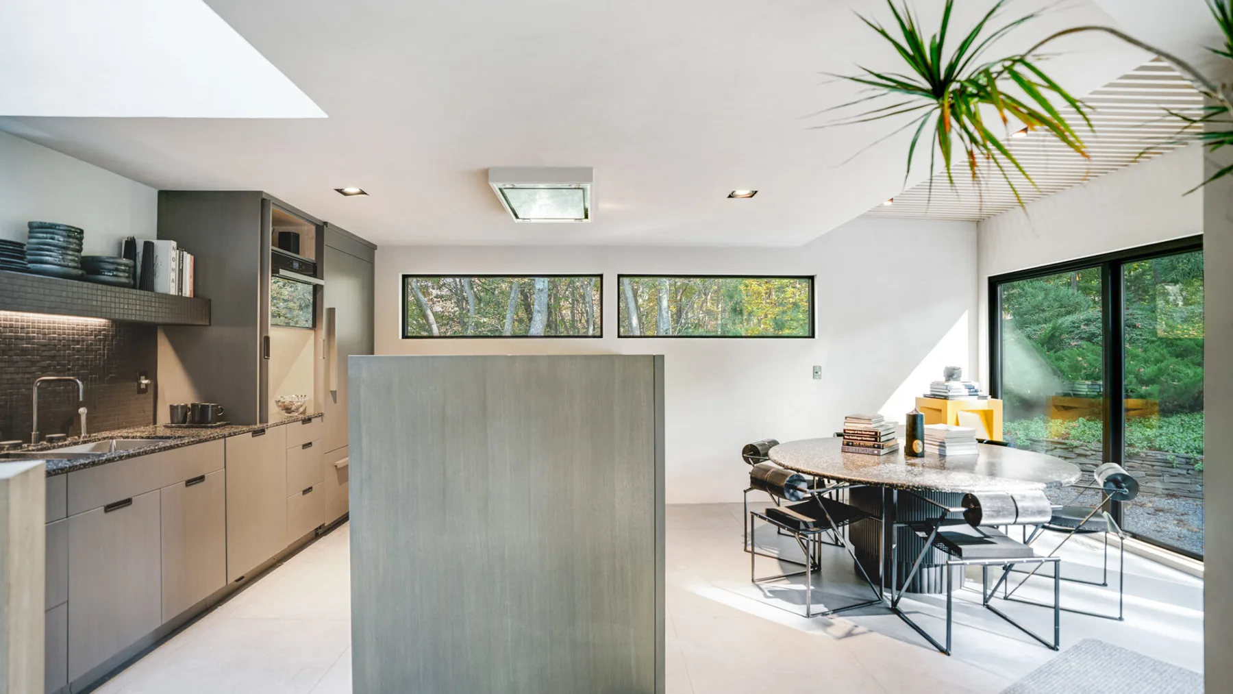 Una cocina moderna y zona de comedor con una mesa grande junto a puertas de vidrio.