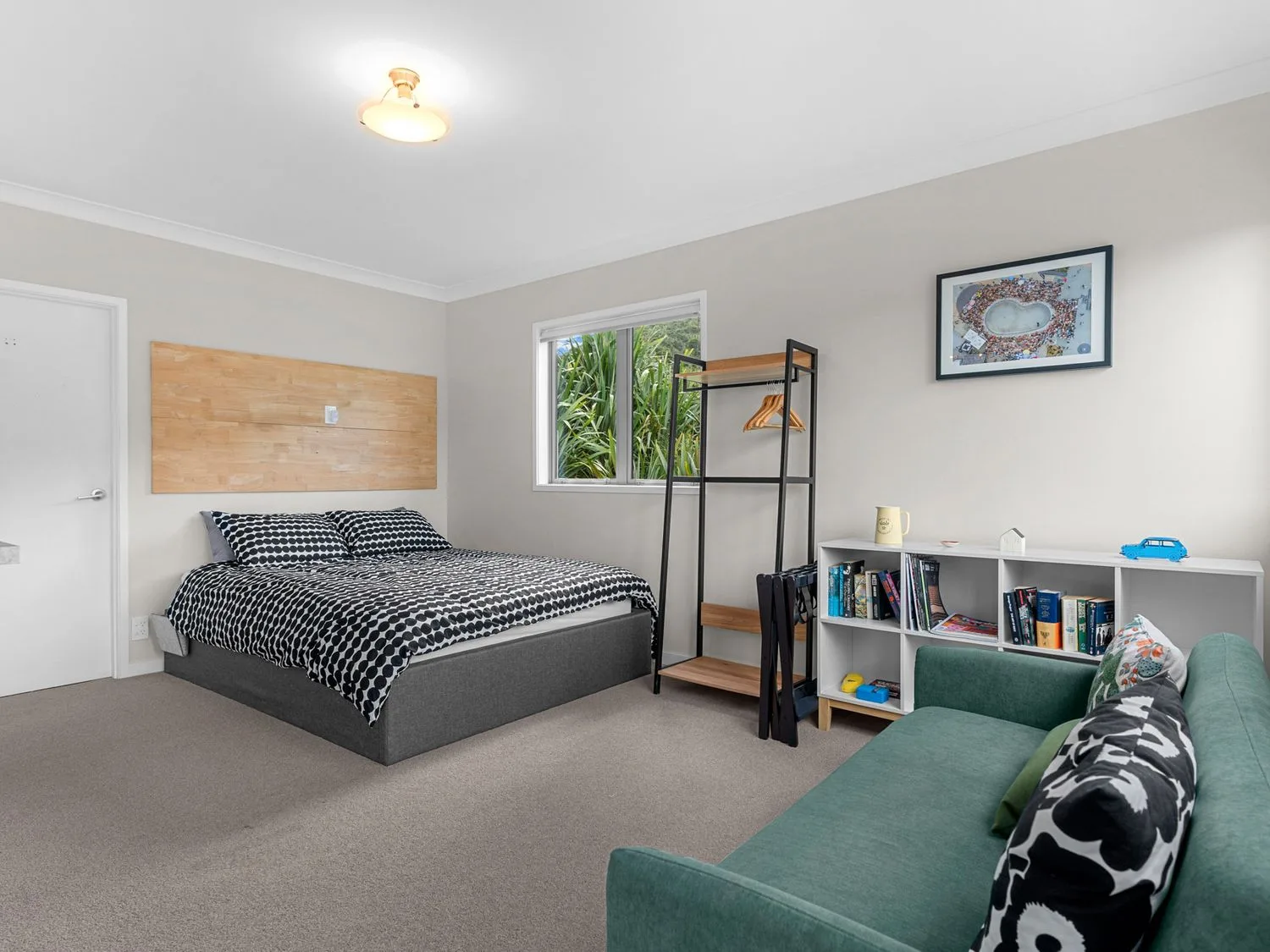 Un dormitorio con una cama, un sofá verde, una estantería y un perchero en Pearl's Embrace - Mangawhai Heads Studio, en Mangawhai Heads