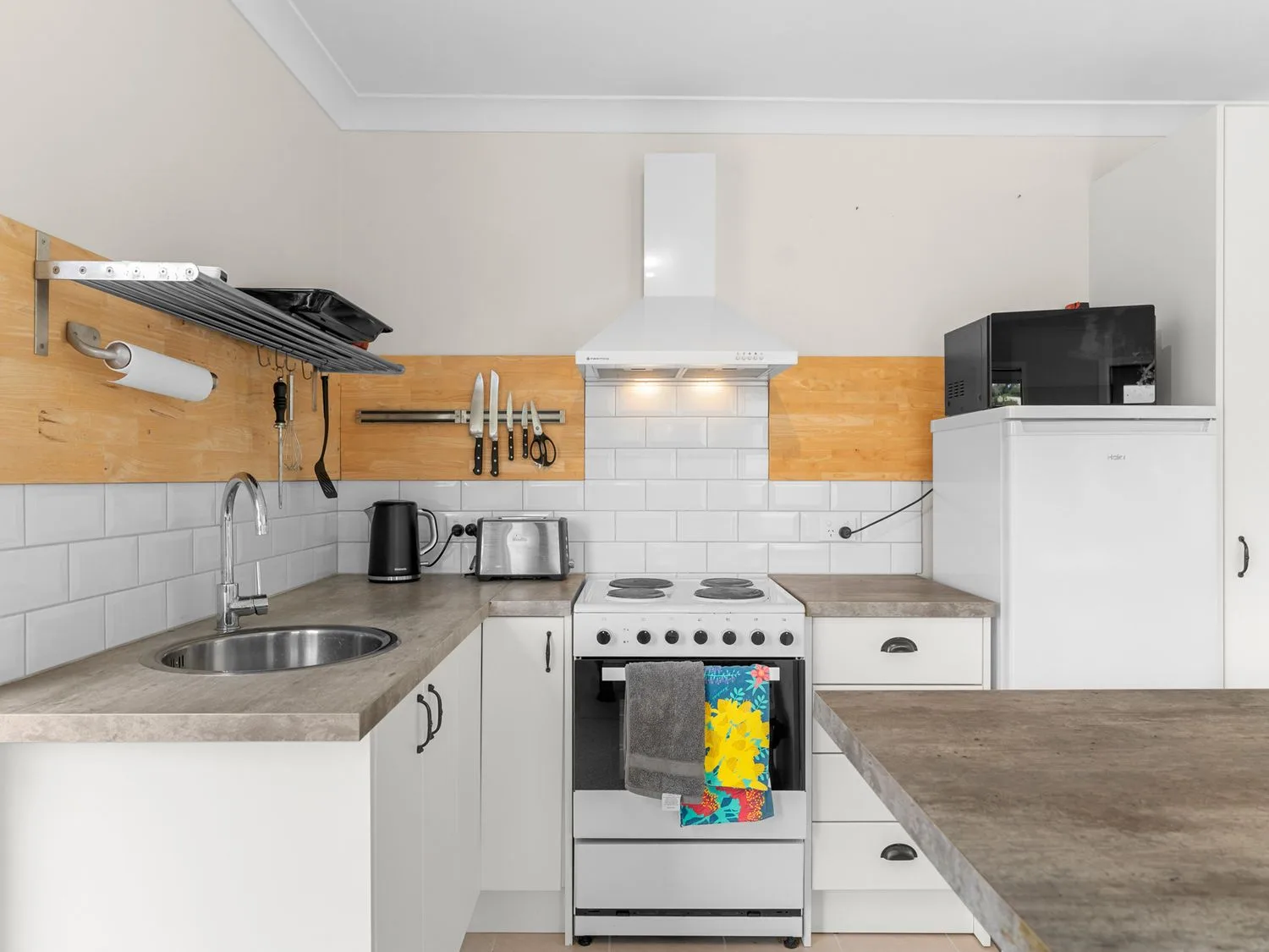 Una cocina con fregadero, hervidor, cocina, horno y refrigerador.