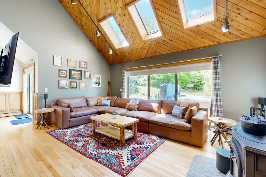 A bright living room with seating beneath a sloped wooden ceiling and skylights.