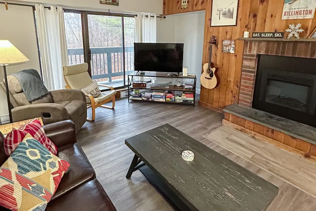 A living room with seating, a television, and a fireplace.