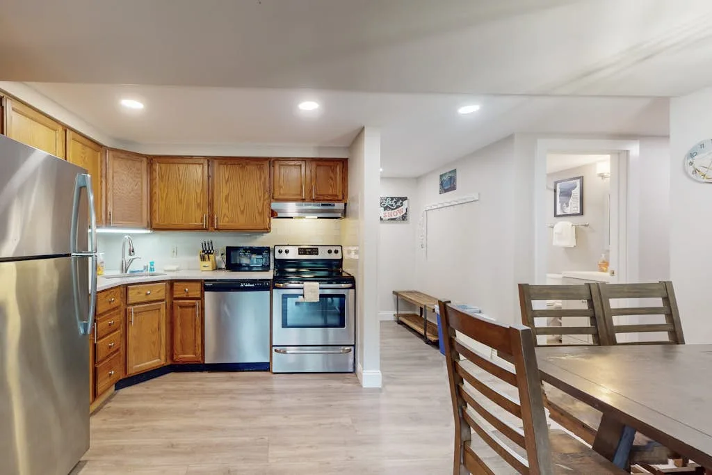 An open-plan kitchen and dining area with wooden cabinets and a dining table.
