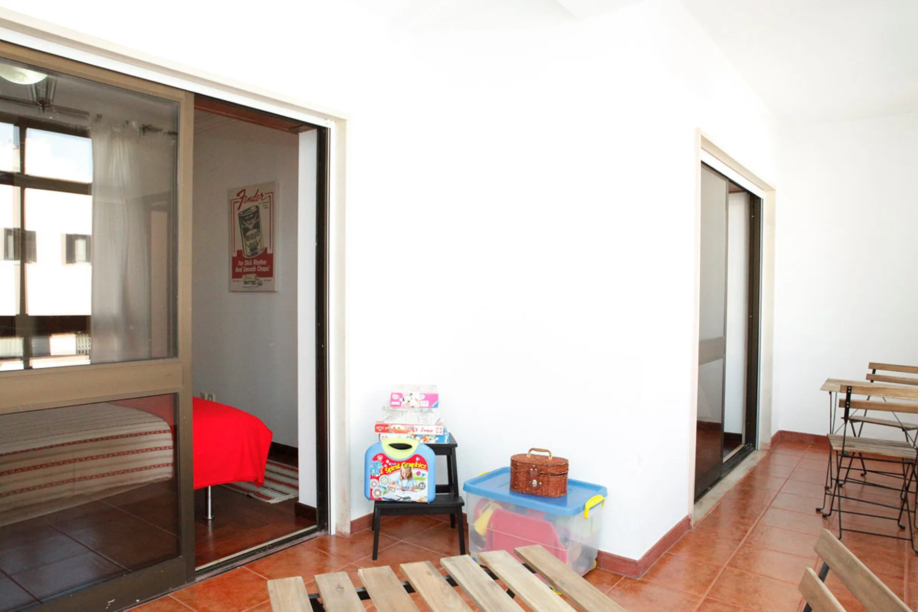 Una habitación luminosa con una cama visible tras puertas correderas de vidrio y una mesita.
