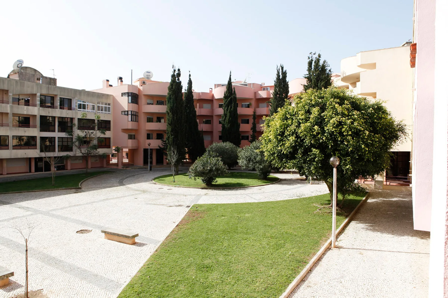 Un patio residencial con un sendero pavimentado, césped y edificios de apartamentos alrededor.
