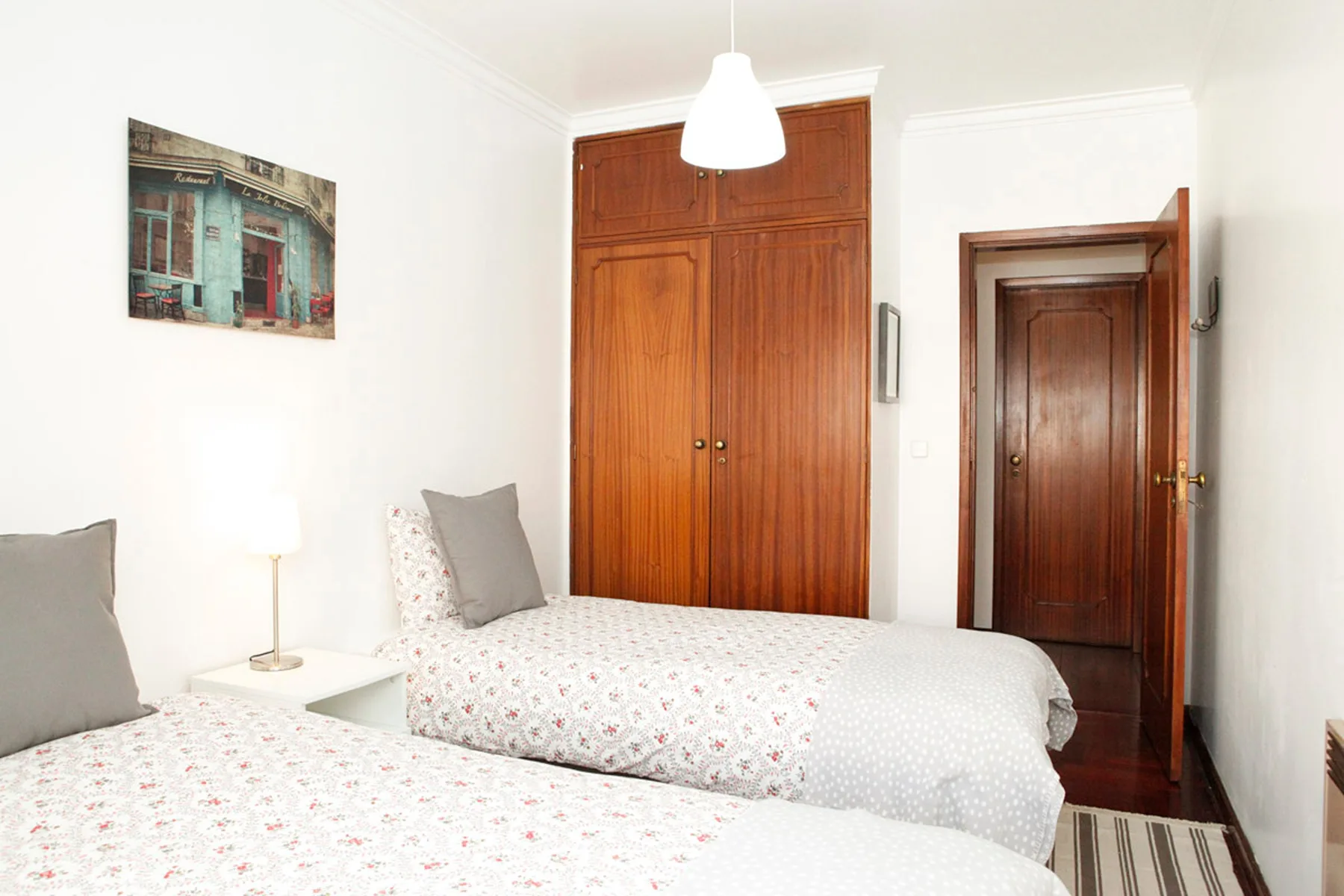 Dormitorio con dos camas, un armario de madera y una puerta abierta.
