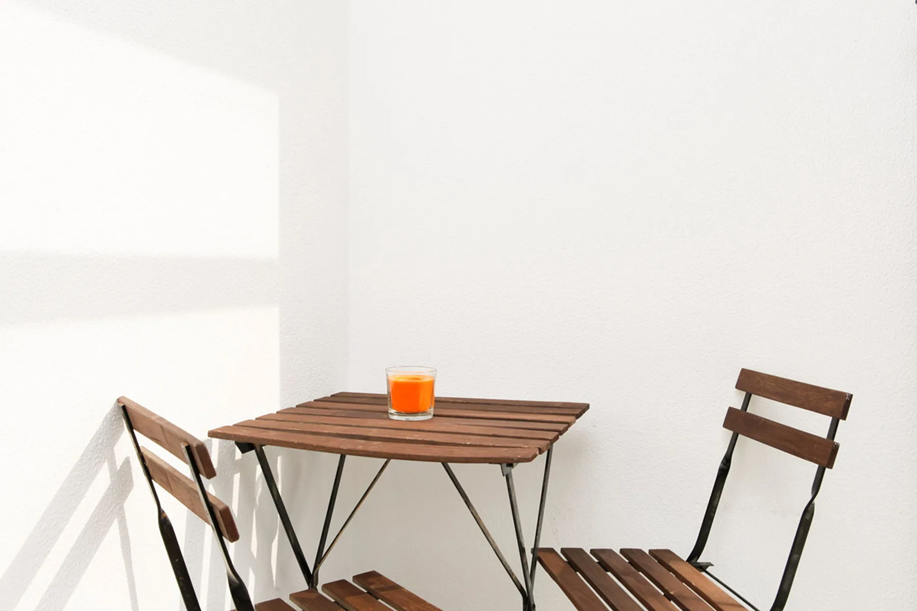 Una pequeña zona de estar en un patio, con una mesa y sillas de madera.