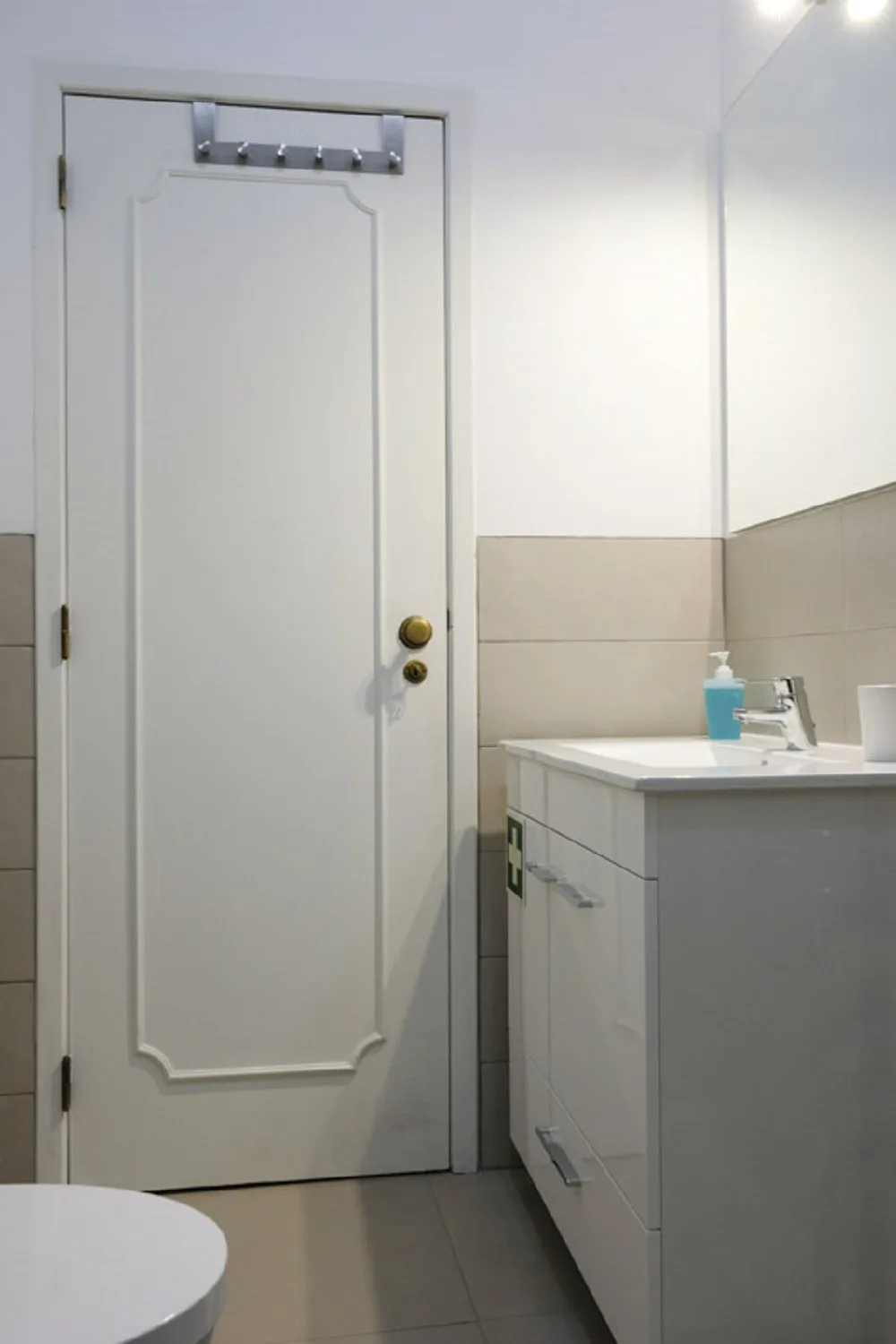Un baño con un lavabo y un mueble junto a una puerta blanca.