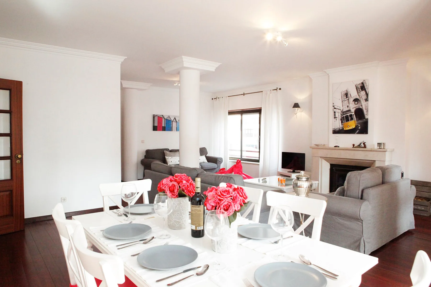 Una zona de comedor con la mesa puesta está junto a una sala de estar con asientos.