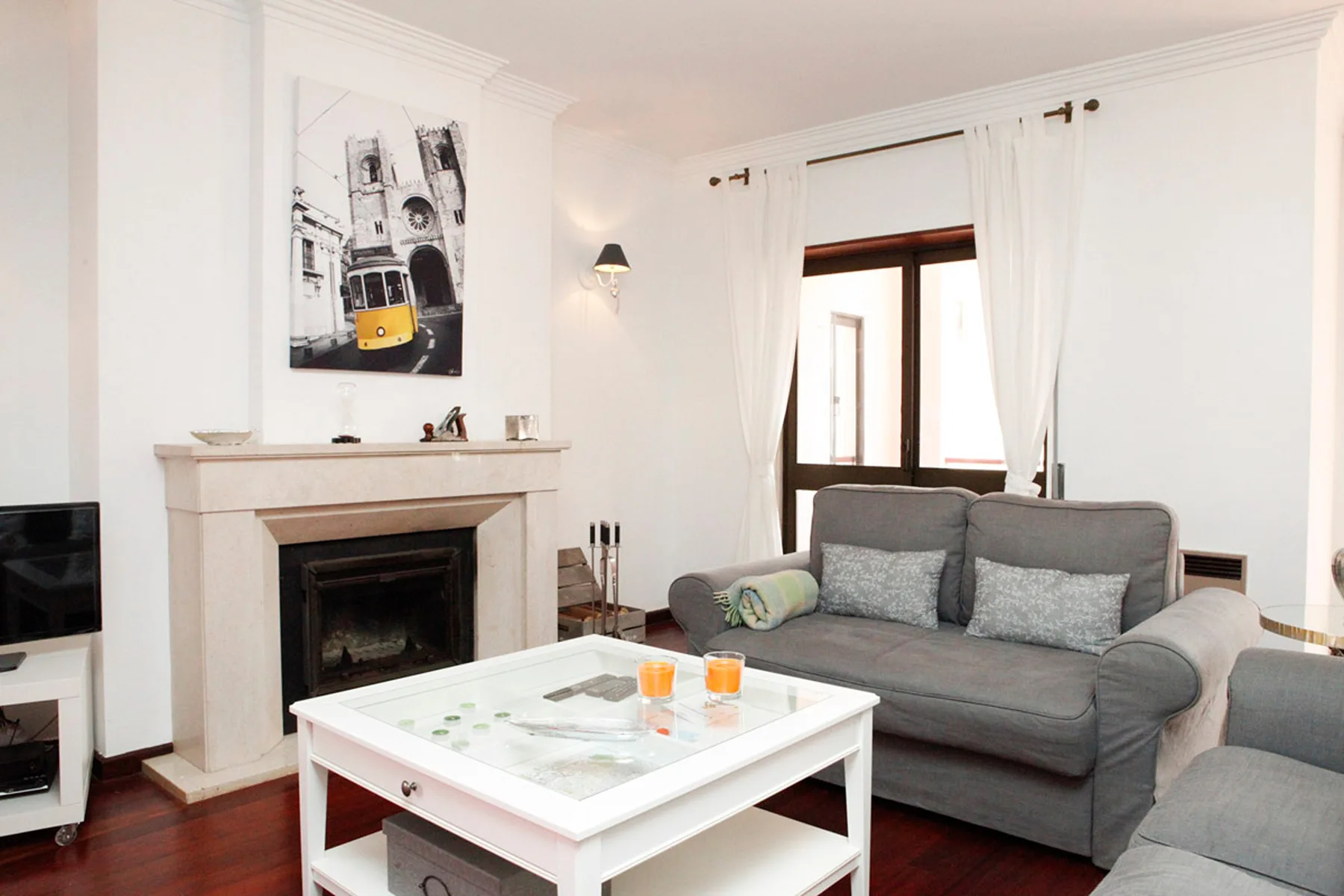 Sala de estar con un sofá gris, una chimenea y una mesa de centro blanca.
