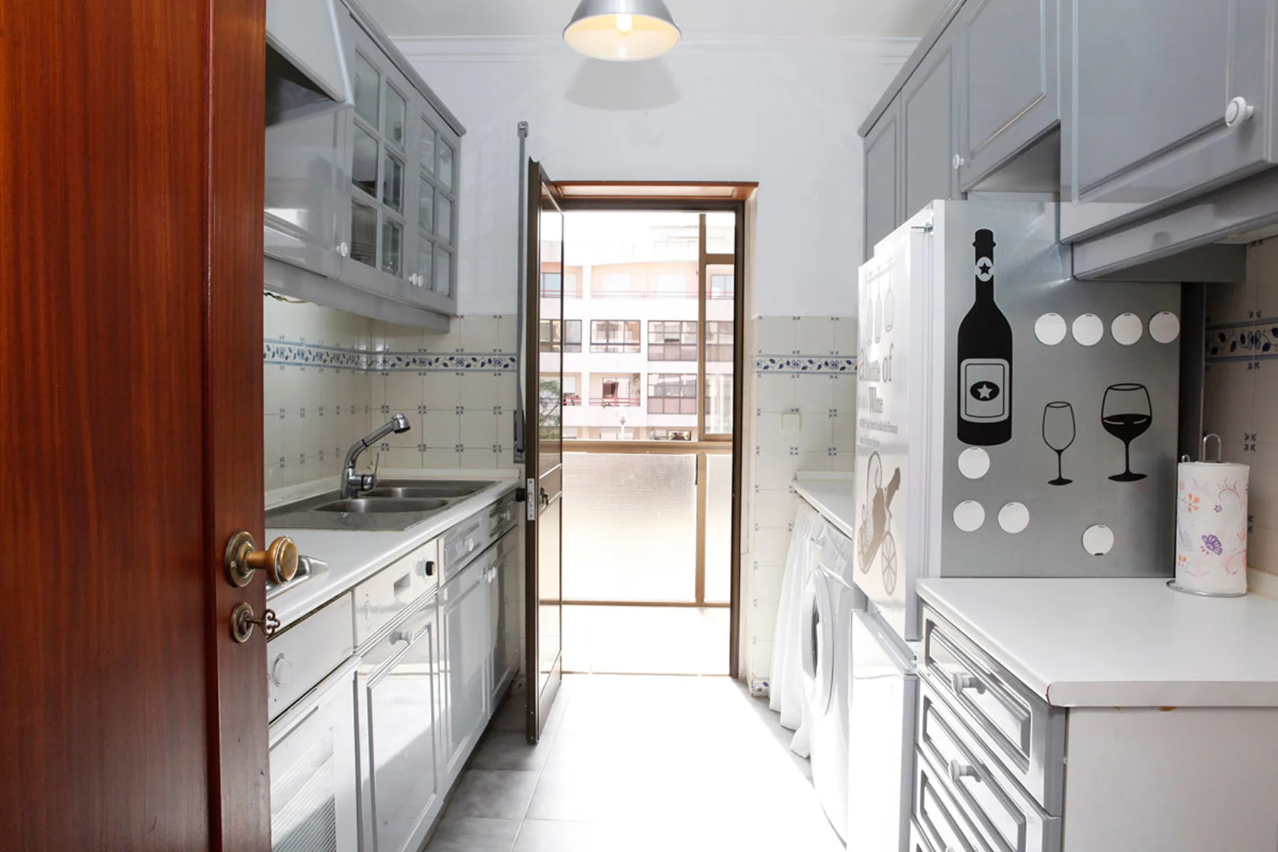 Una cocina estrecha con armarios, fregadero y lavadora.