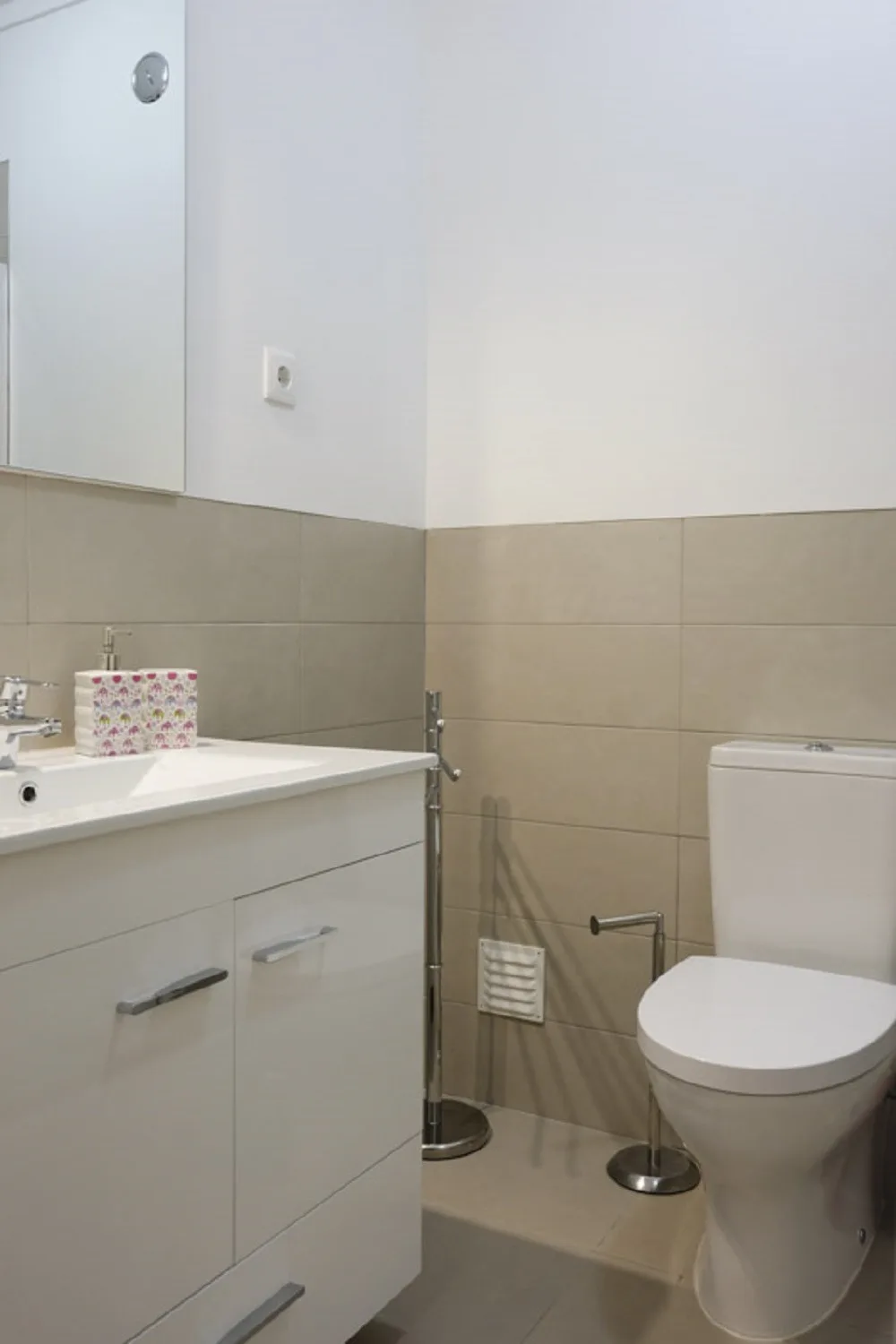 Un baño con lavabo y váter junto a paredes alicatadas.