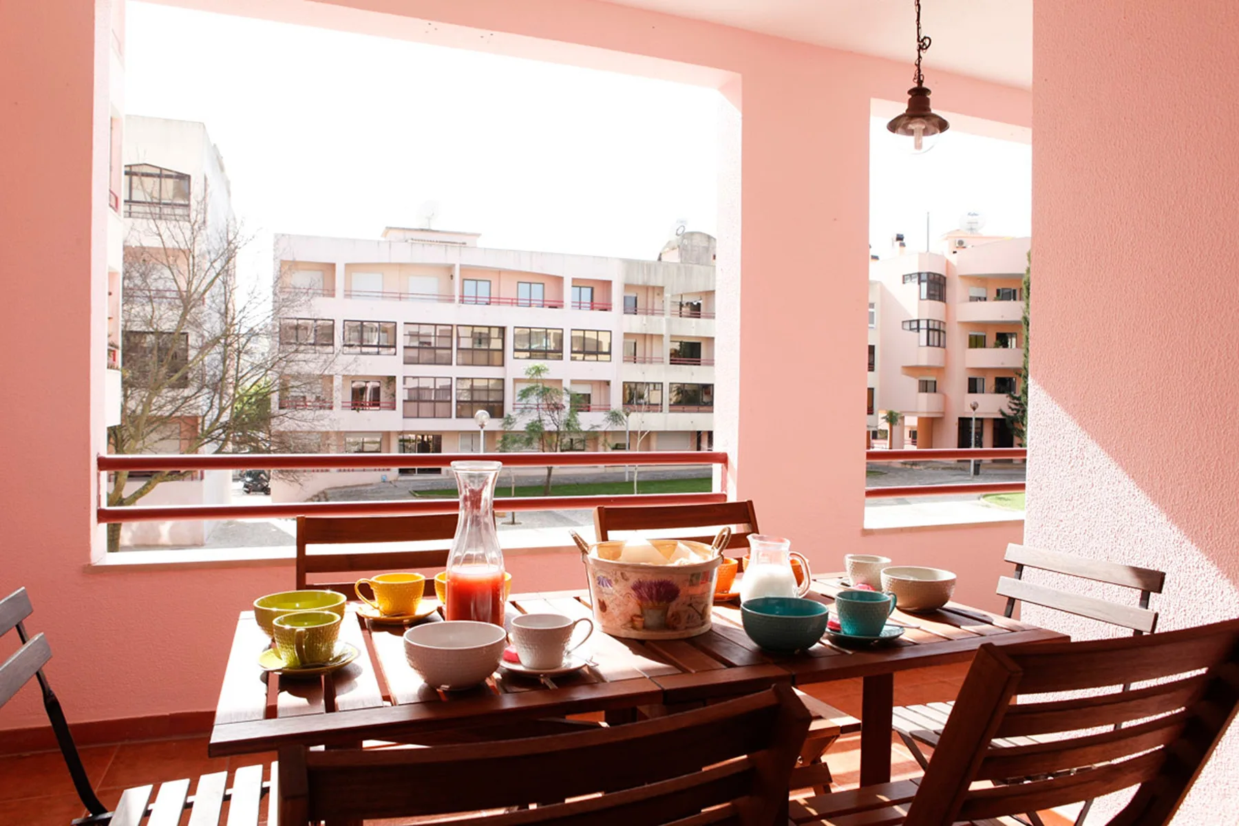 Una zona cubierta para comer, con la mesa puesta, da a edificios cercanos.