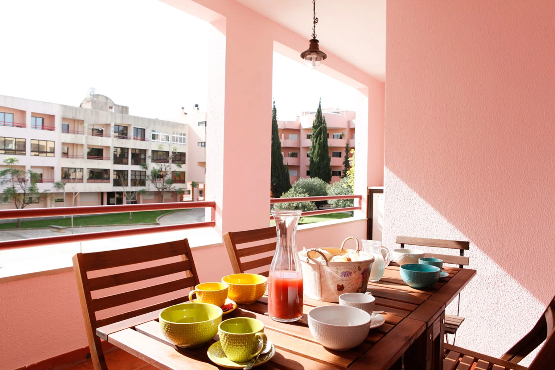 Una zona cubierta para comer al aire libre con una mesa de madera preparada con cuencos y bebidas.