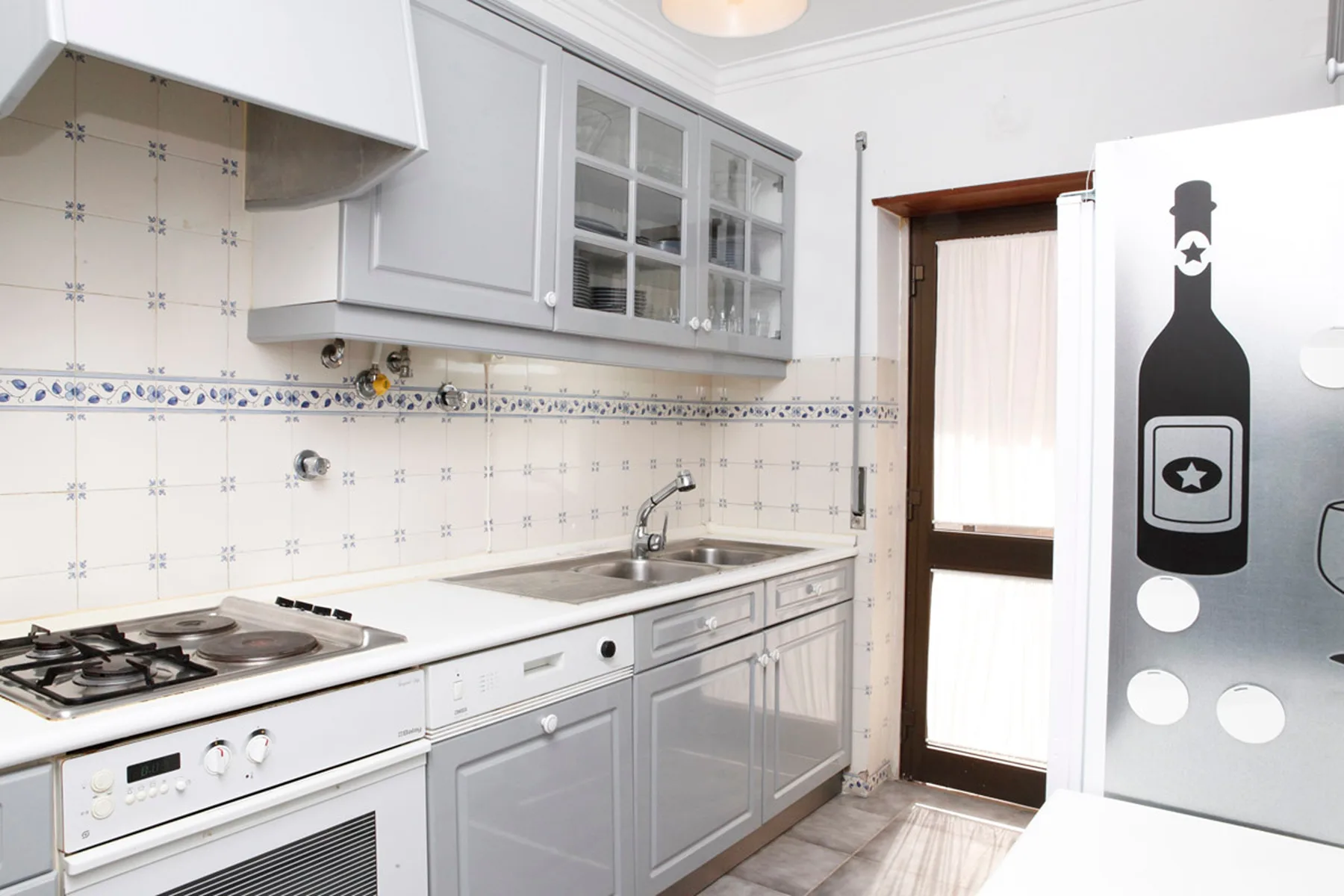 Una cocina luminosa con armarios blancos, un salpicadero de azulejos y una placa de cocina.