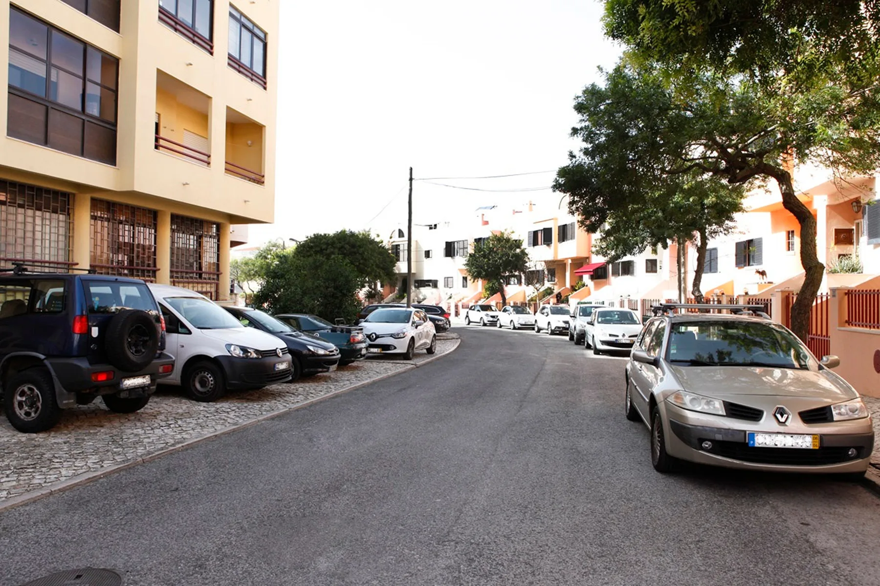 Una calle residencial con coches aparcados y edificios de apartamentos.