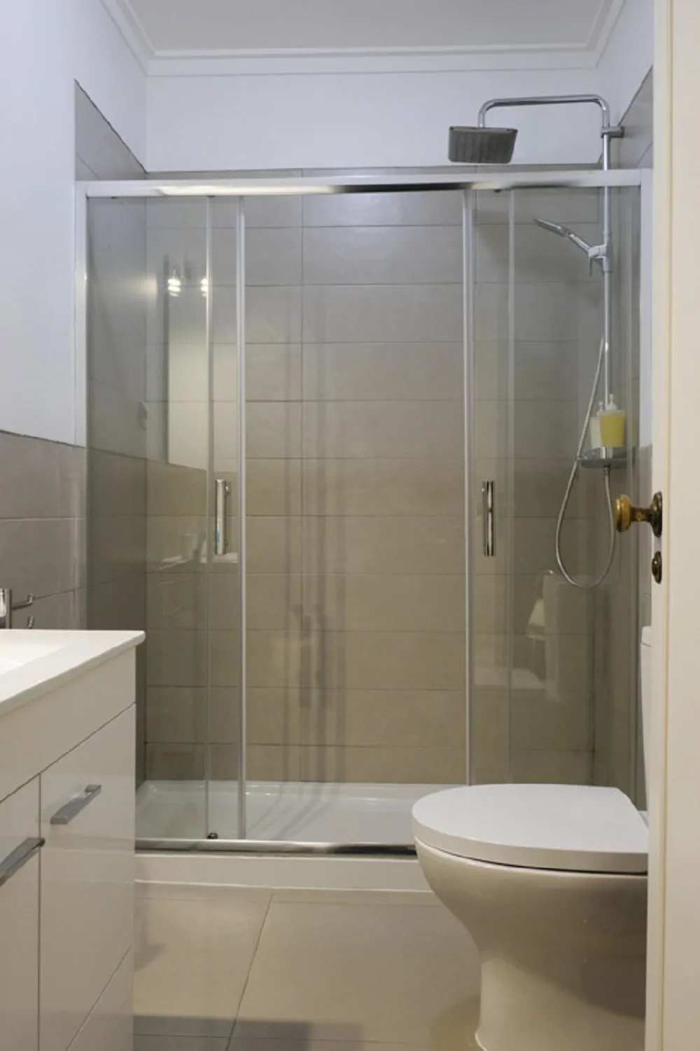 Un baño con una ducha con mampara de vidrio y un inodoro.