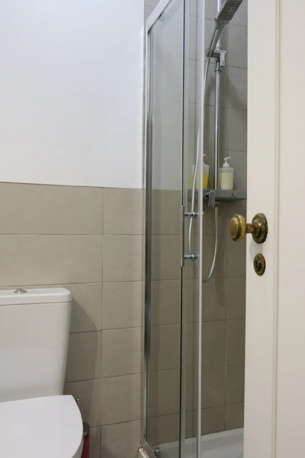 Un baño con una ducha de vidrio y paredes revestidas de azulejos.