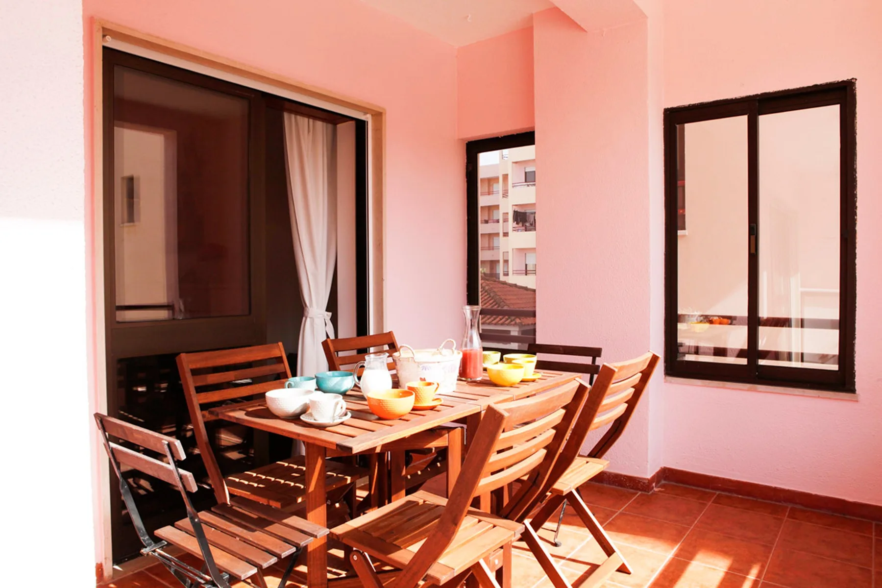 Un comedor con una mesa y sillas de madera está junto a grandes ventanas.