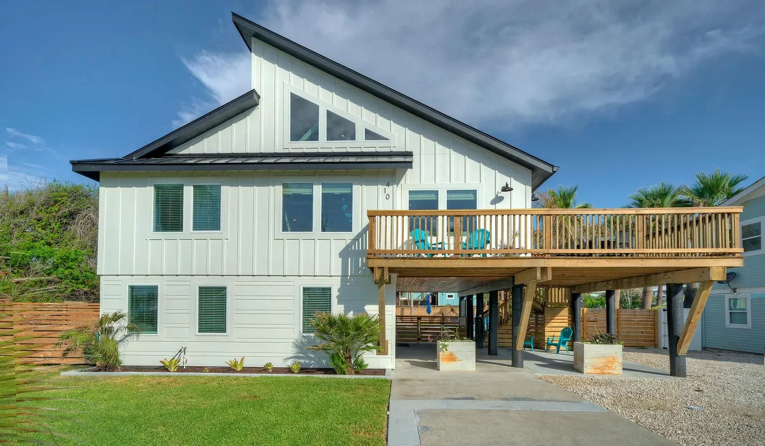 A modern house with a raised wooden deck and a small lawn in front.