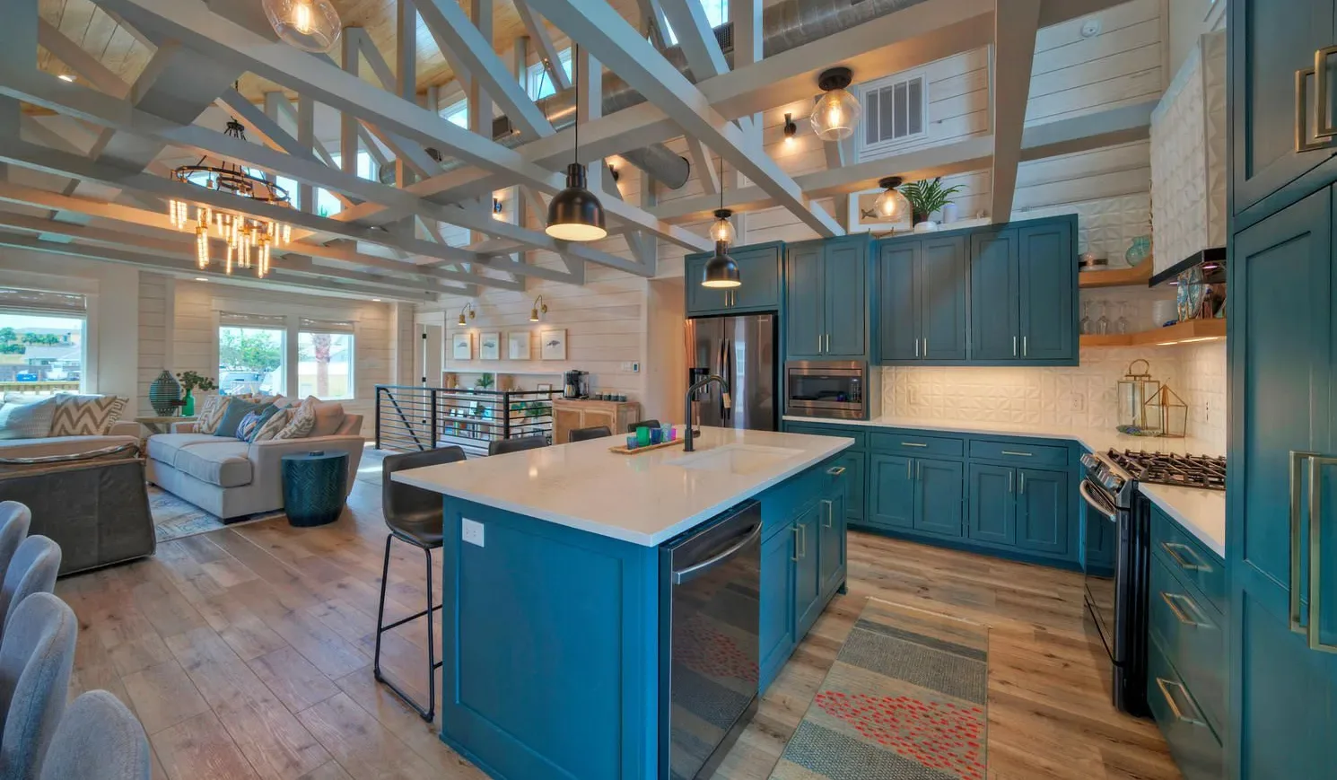 An open-plan kitchen and living area features a central island and exposed ceiling beams.