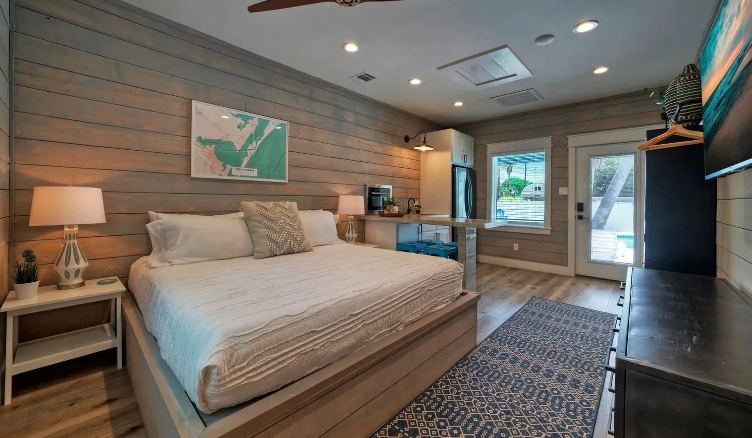 A bedroom with a large bed, wood-paneled walls, and a patterned rug.