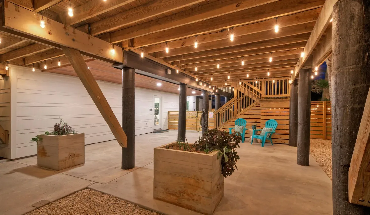 A covered patio with wooden beams, planter boxes, and turquoise outdoor seating.