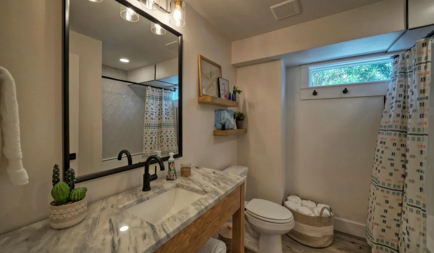 A bathroom with a marble vanity, toilet, and patterned shower curtain.