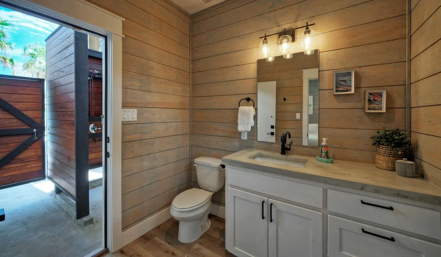 A bathroom with a vanity, mirror, and toilet beside an open doorway.