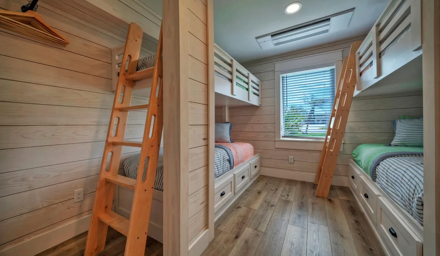 A wood-paneled bunk room with built-in beds and a central window.