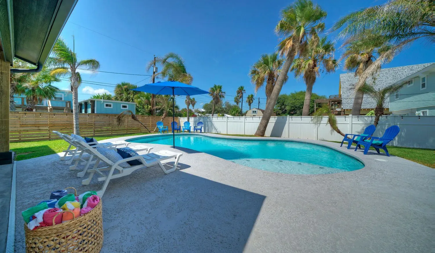 An outdoor swimming pool with lounge seating and a blue umbrella.