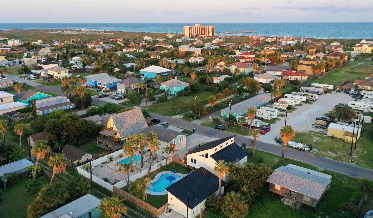 Aerial view of a coastal neighborhood with homes and a swimming pool.