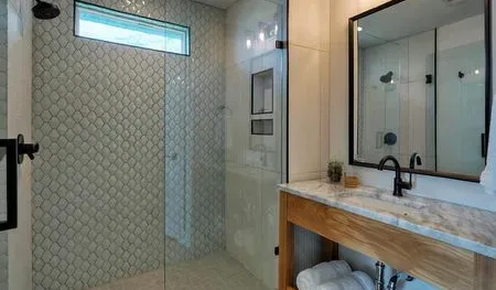 A tiled bathroom with a glass shower and a vanity beside a large mirror.
