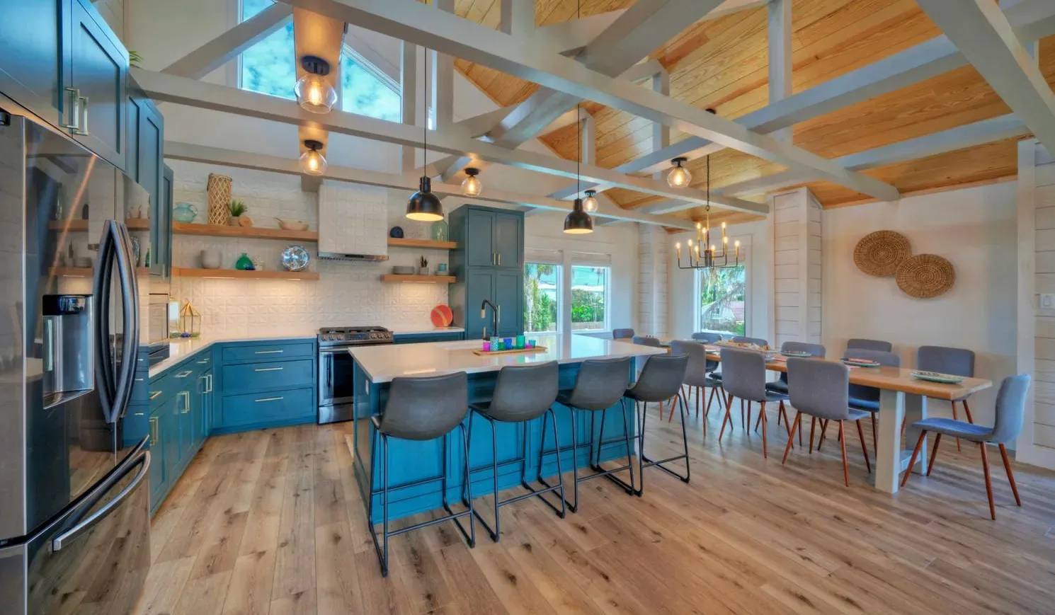 An open kitchen and dining area has blue cabinets and a long island.