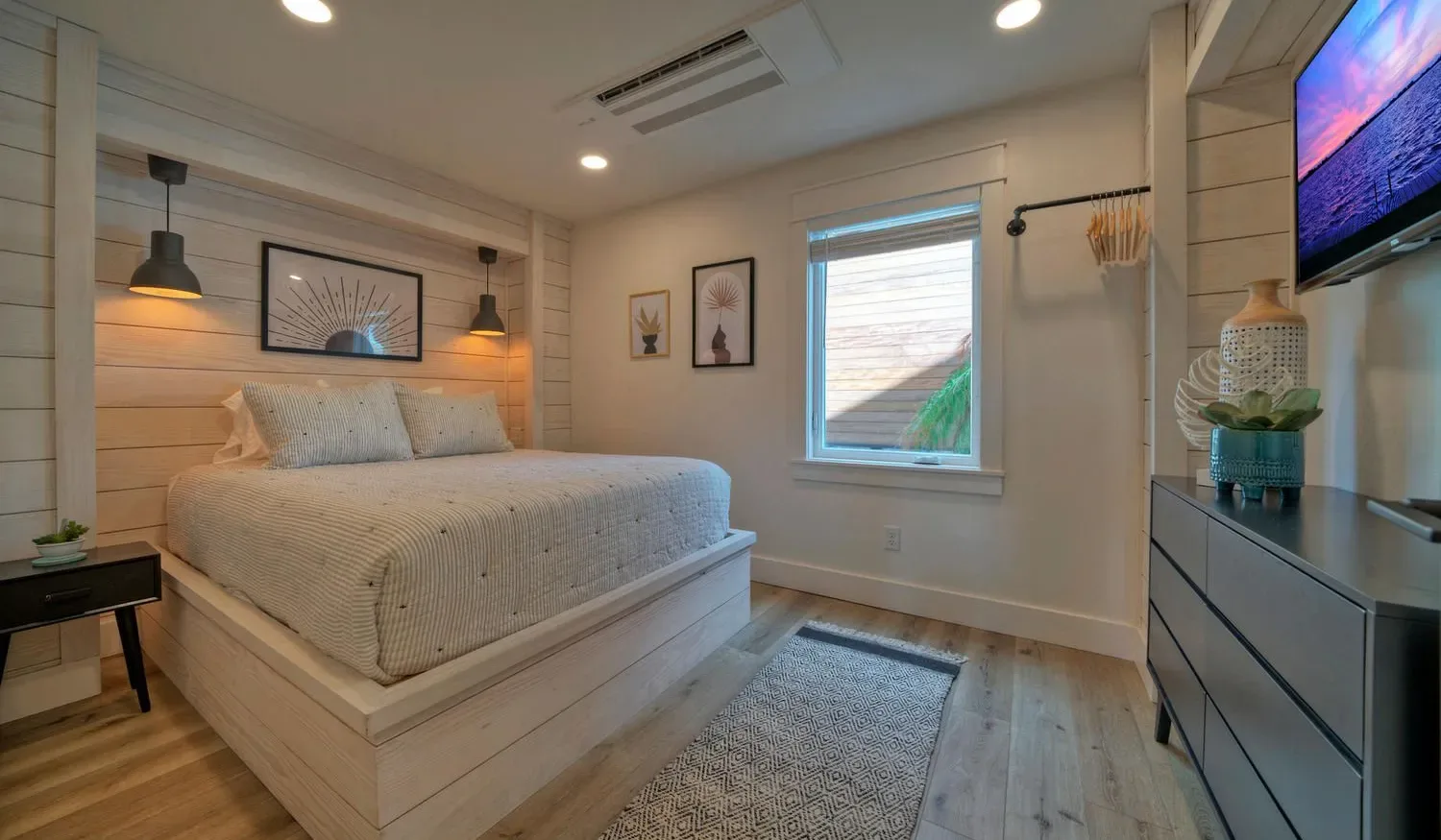 A bedroom with a raised bed, a window, and a dresser.