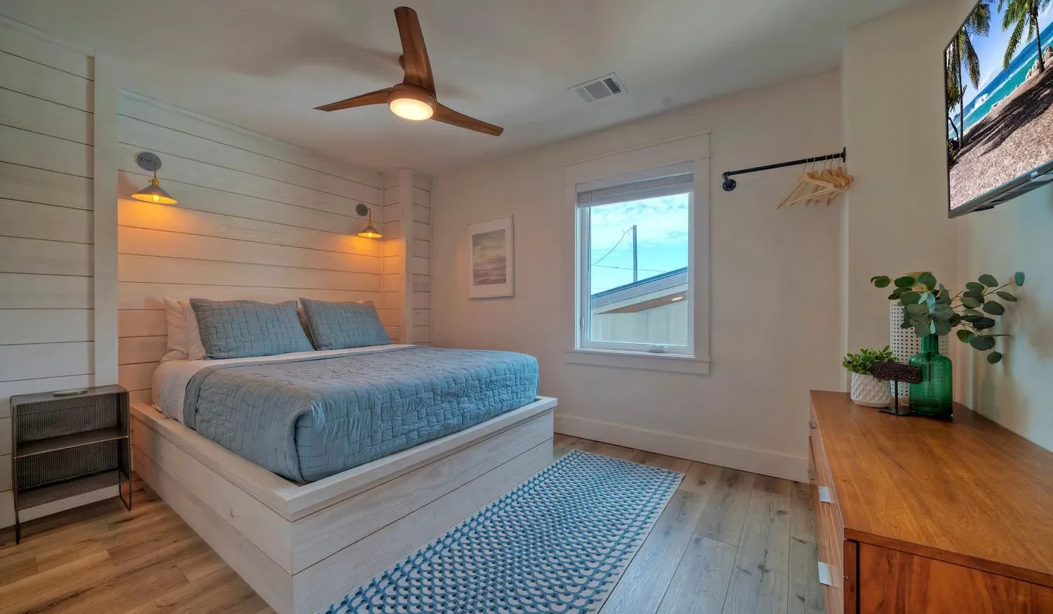 A bedroom with a bed, blue bedding, and a ceiling fan.