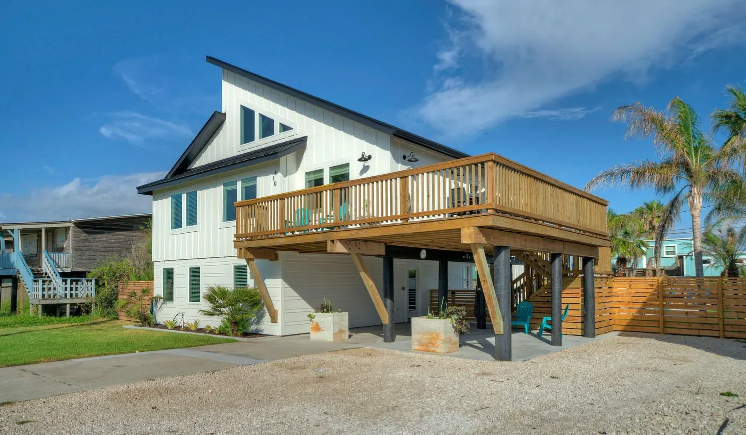 A raised coastal-style house with a wooden deck and stairs.