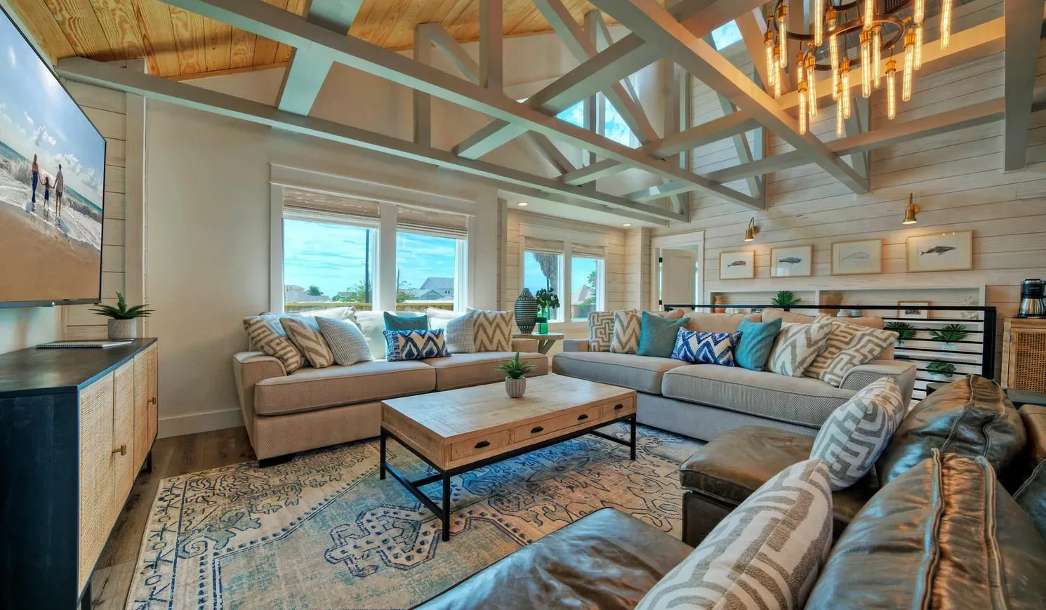A spacious living room with sectional seating beneath exposed ceiling beams.