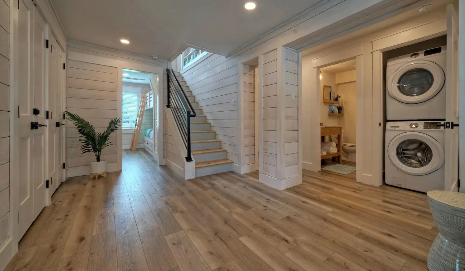 A bright hallway with a staircase and laundry appliances.