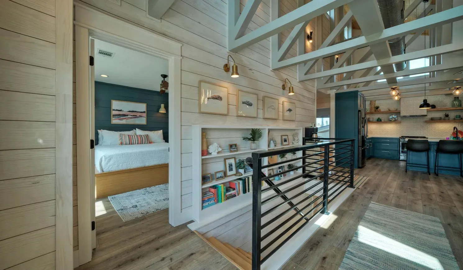 A lofted interior with a bedroom, built-in shelves, and a railing along the upper level.