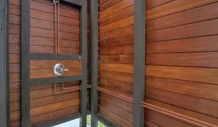 A wood-paneled shower area with a metal shower fixture.