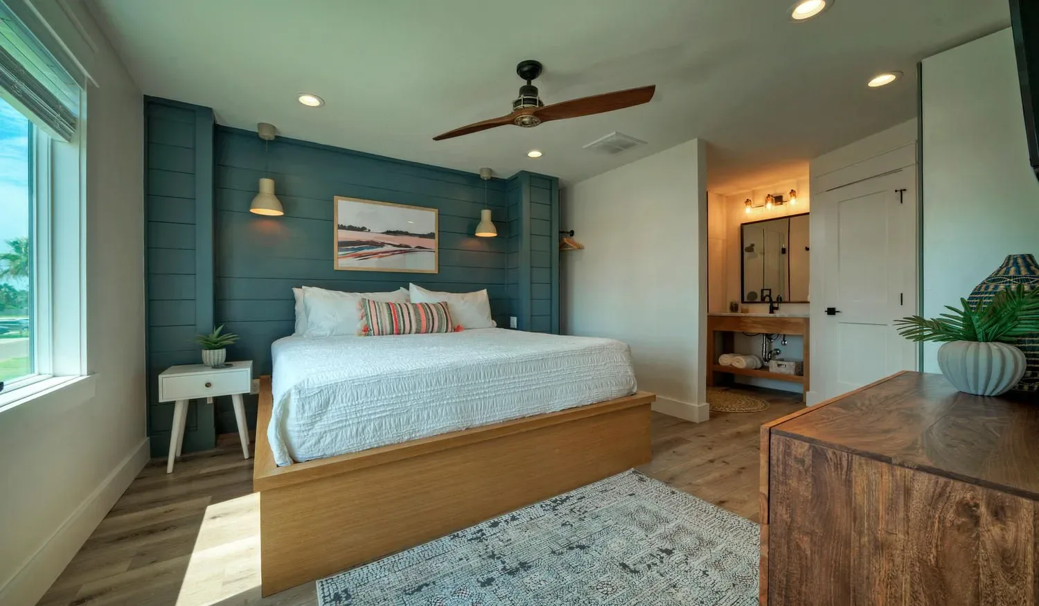 A bedroom with a neatly made bed, bedside tables, and a ceiling fan.