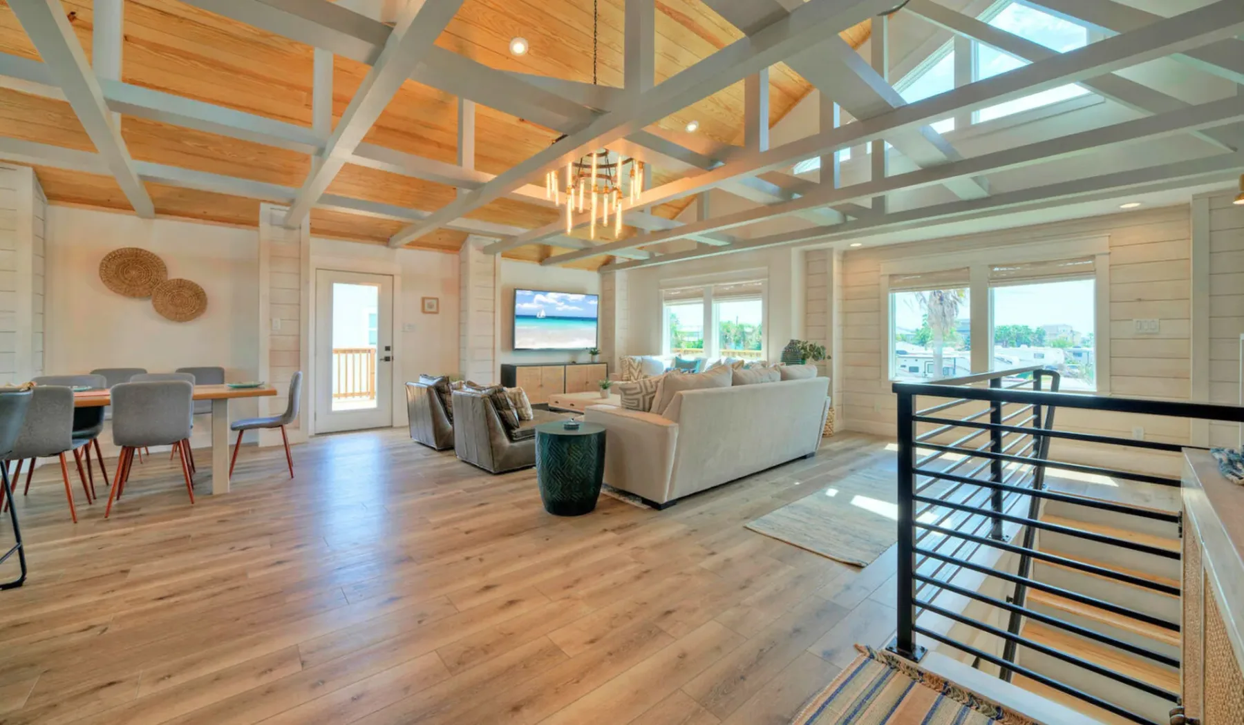 An open living and dining area with seating beneath exposed ceiling beams.
