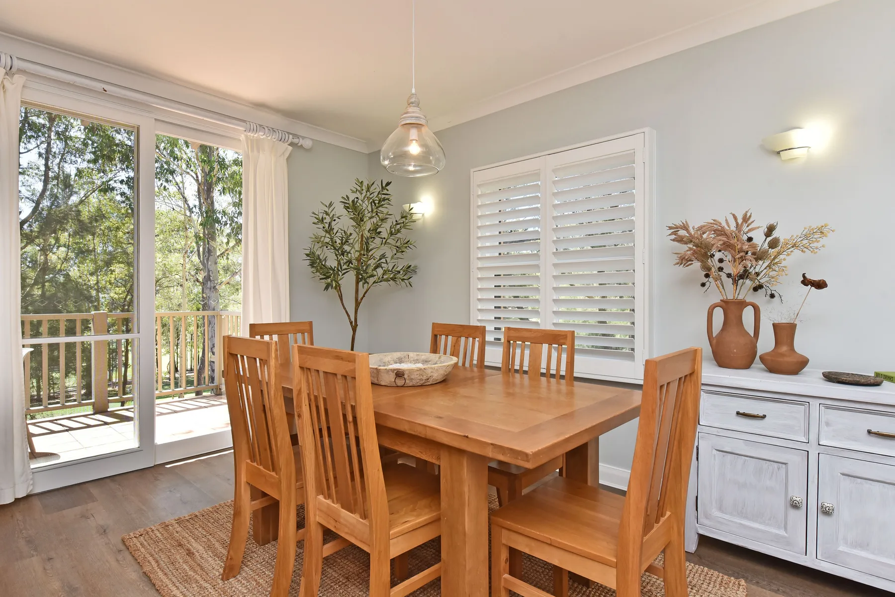 A dining area with a wooden table and chairs beside glass doors opening to a balcony.