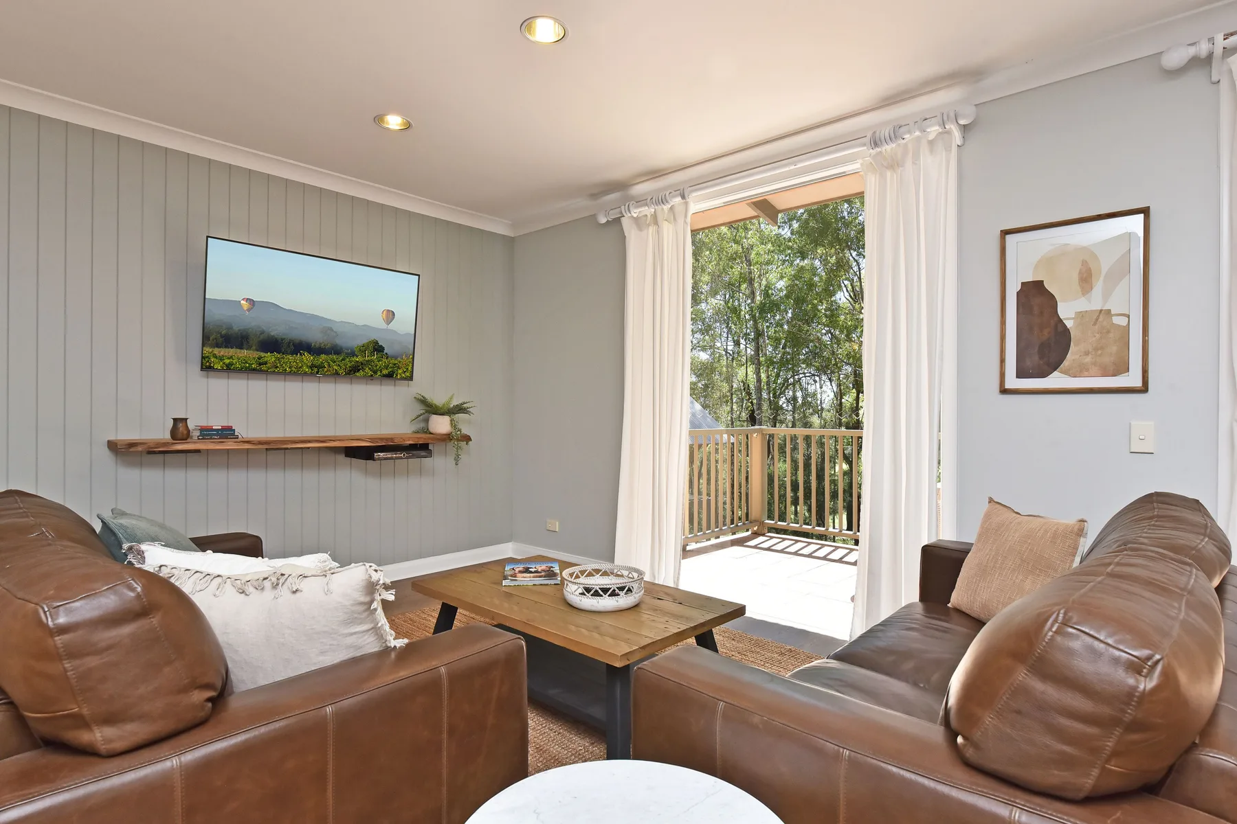 A living room with leather seating, a coffee table, and glass doors opening to a balcony.