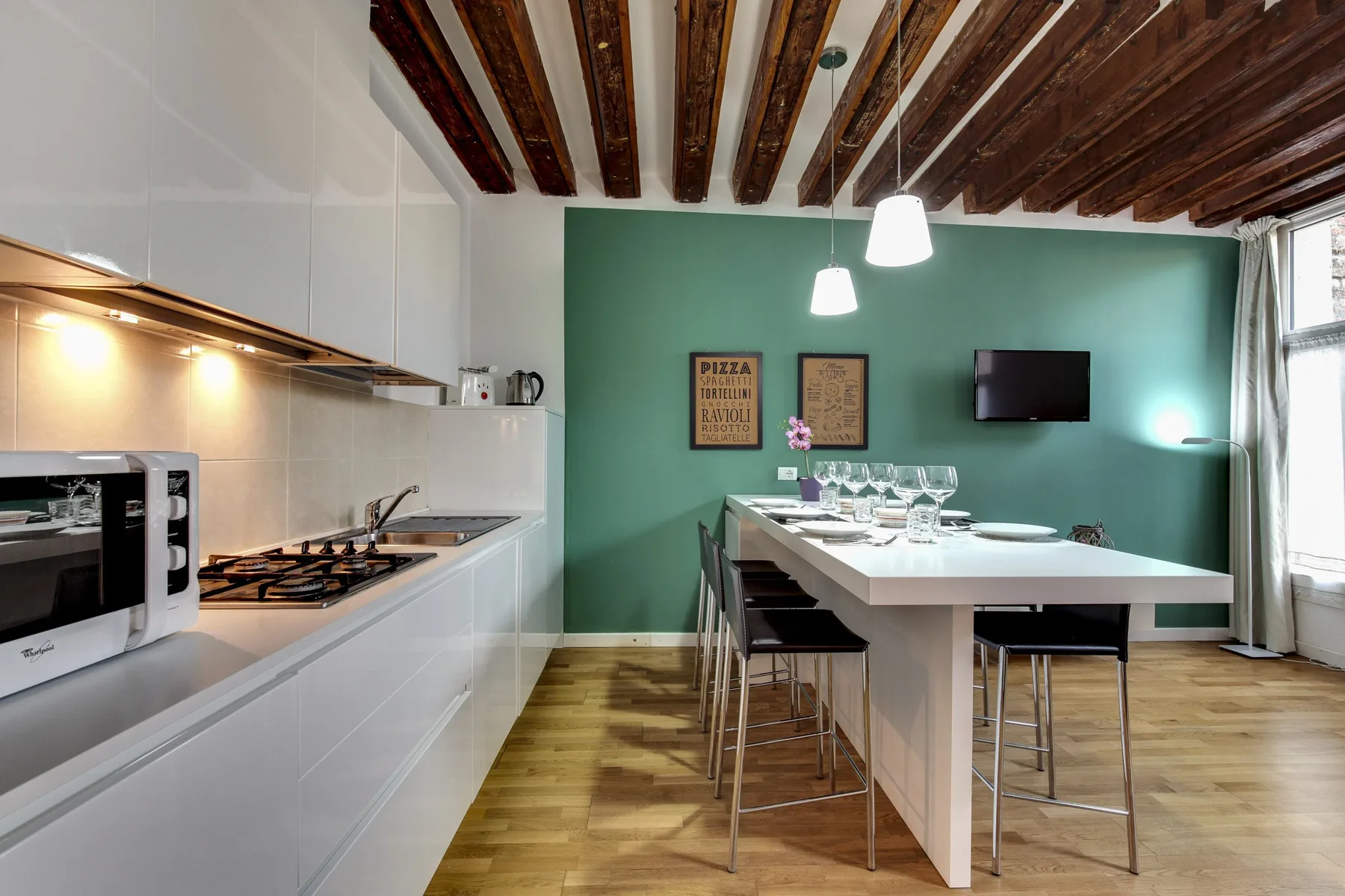 A modern kitchen and dining area with a long table beside white cabinetry.