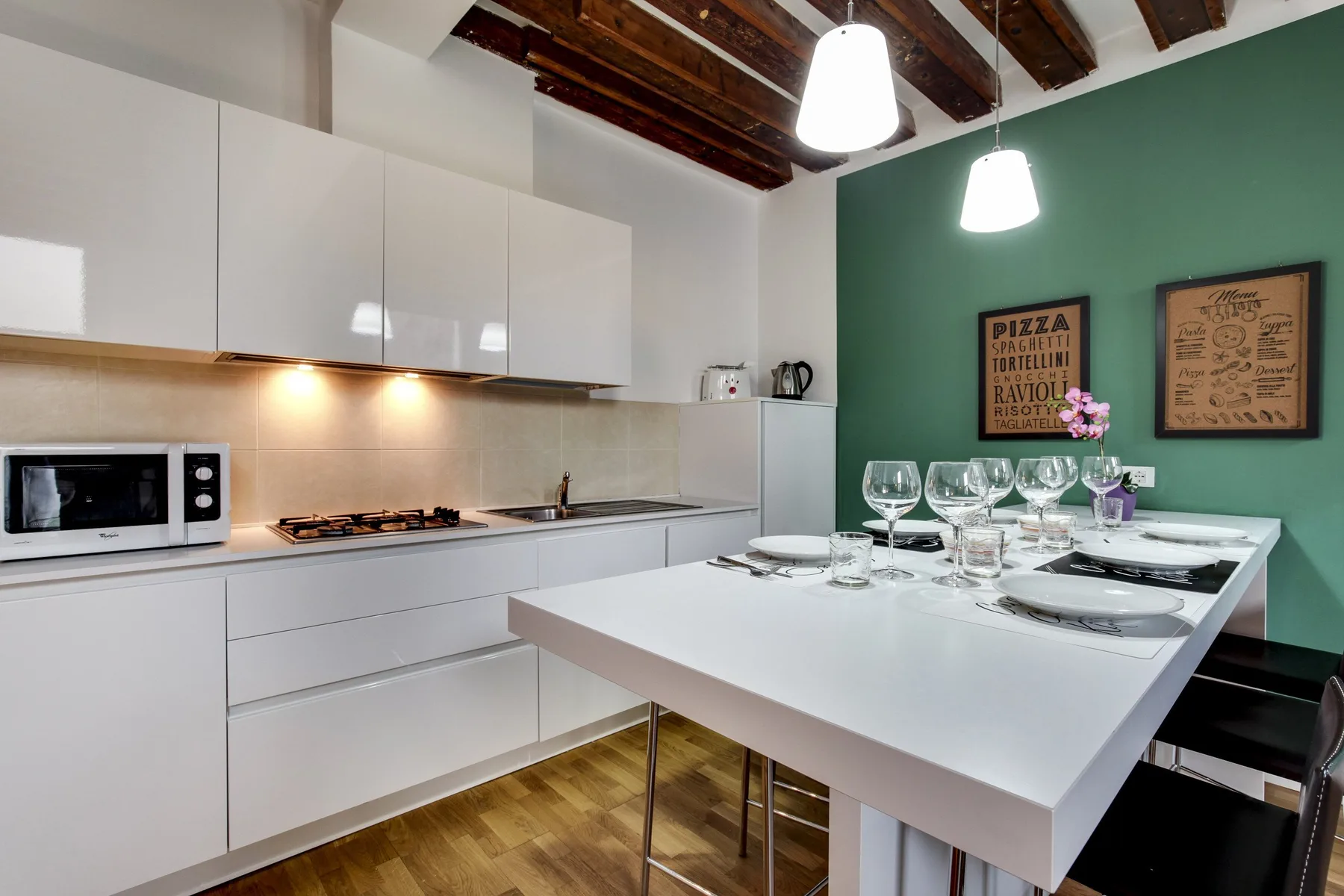 A modern kitchen and dining area with a white table set for a meal.