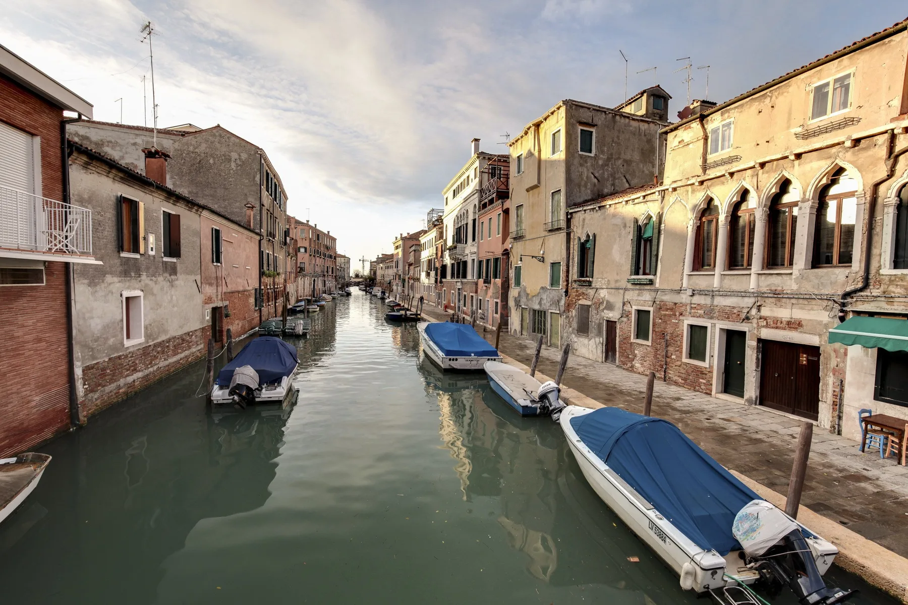 A narrow canal runs between rows of historic buildings, with boats moored along the water.