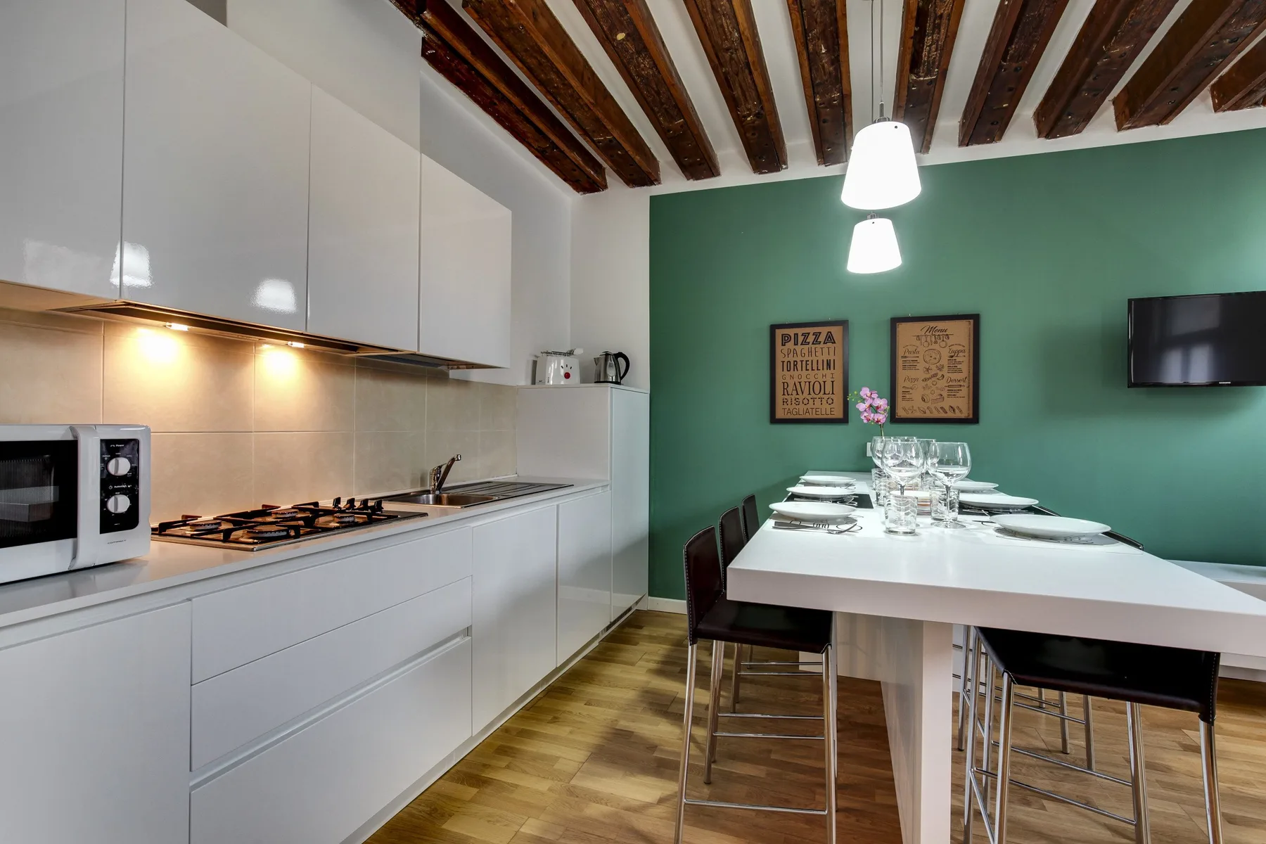 A modern kitchen and dining area features white cabinetry and a long table.